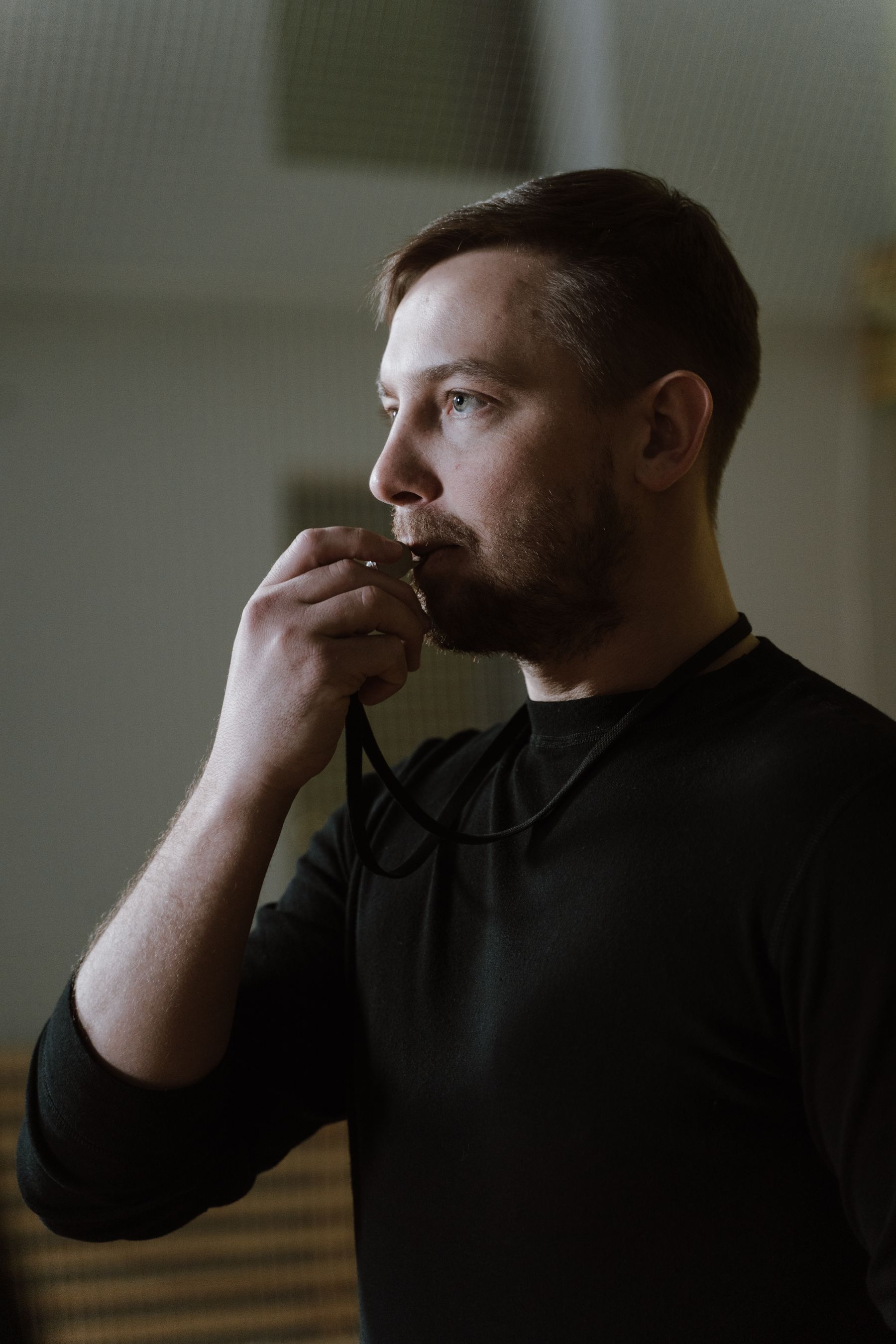 Coach in professional black training attire using a whistle