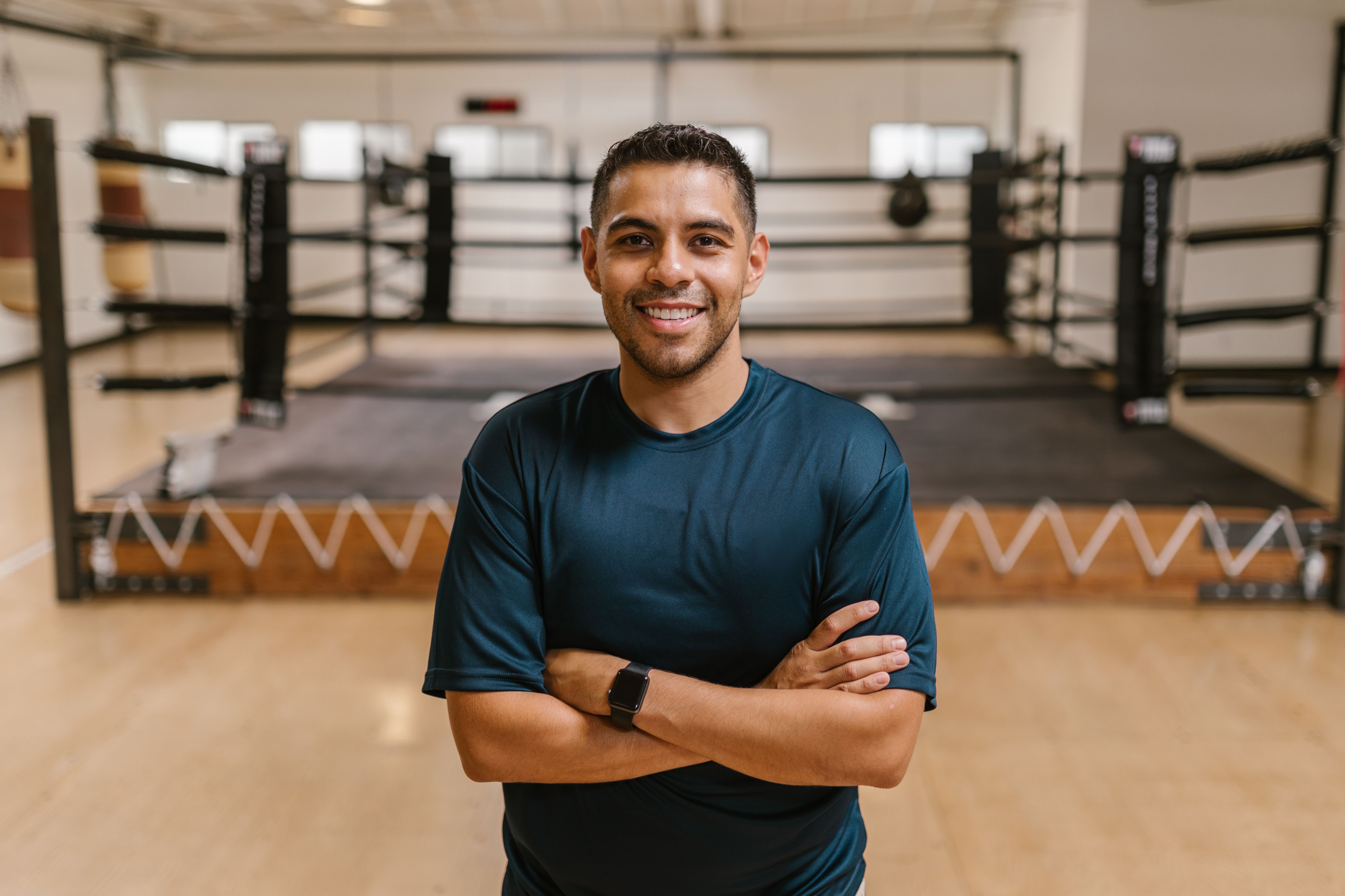 Confident fitness professional in a clean navy training shirt at a boxing gym